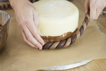 Twists of icing being put around cake to give basket effect