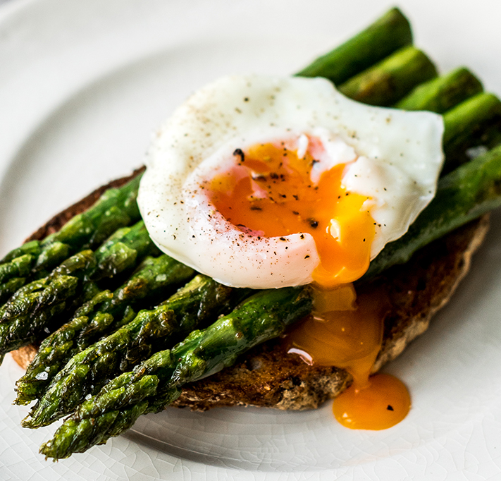 running poached egg on asparagus and brown toast