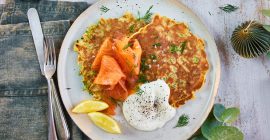 A plate of Brussels sprout savoury pancakes, accompanied by smoked salmon and lemon wedges.