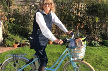 A lady sits on a blue bike