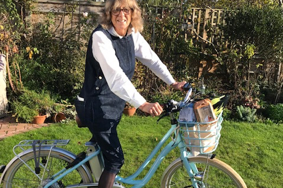 A lady sits on a blue bike