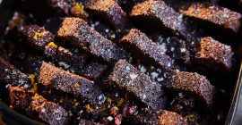 A closeup of baked gingerbread pudding sprinkled with sugar and orange zest