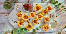 A board of quail egg pastries, surrounded by Christmas foliage.