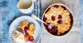 A dish of baked raspberry and almond sponge, next to a plate of the sponge with cream