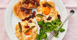 Chorizo and sage cloud eggs sit on a round white plate on a light pink table