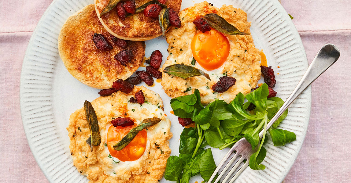 Chorizo and sage cloud eggs sit on a round white plate on a light pink table