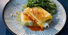 Two sweet and salty egg crisp parcels sit on a stripy black and white plate.