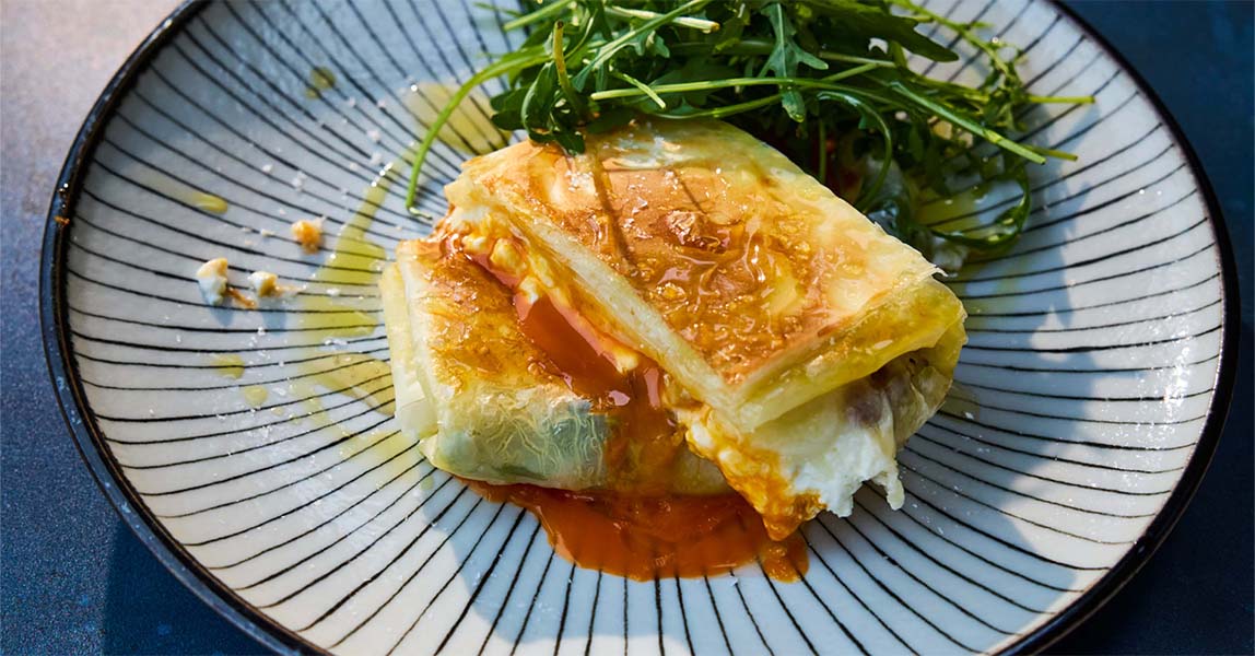 Two sweet and salty egg crisp parcels sit on a stripy black and white plate.